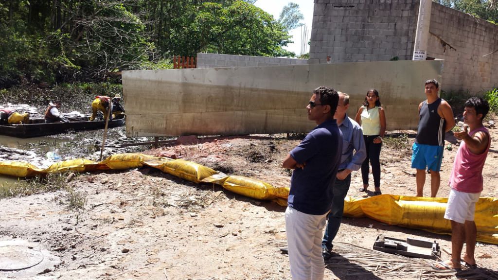 Moradores observam a retirada do óleo. No muro, a marca de onde a água oleosa chegou. Foto: Bruno Lyra